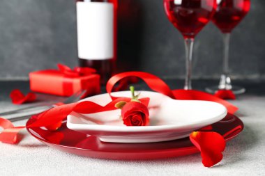Plate with rose flower and ribbon on table. Valentine's Day celebration