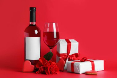 Glass of wine, bottle, rose flowers and gifts on red background. Valentine's Day celebration