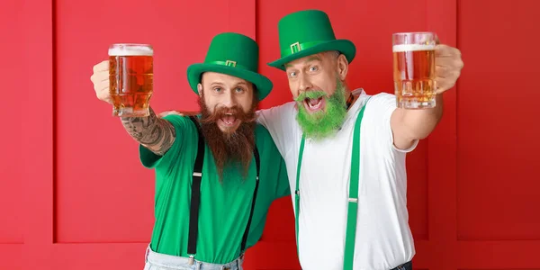 Happy bearded men drinking beer on red background. St. Patrick\'s Day celebration