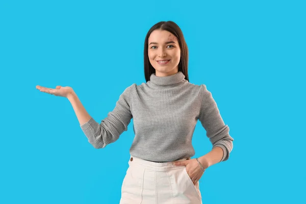 Young Woman Grey Sweater Showing Something Blue Background — Foto Stock