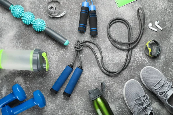 Skipping ropes with sports equipment, bottles, measuring tape and sneakers on dark background