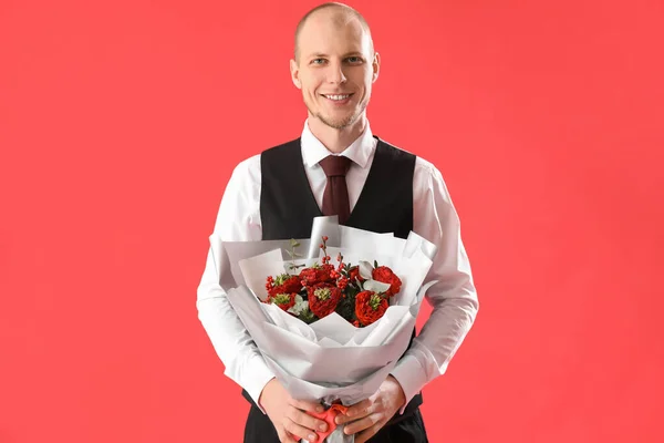 Young man with bouquet of flowers on red background. Valentine\'s Day celebration