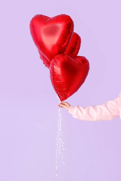 Woman with heart shaped balloons for Valentine\'s Day on lilac background