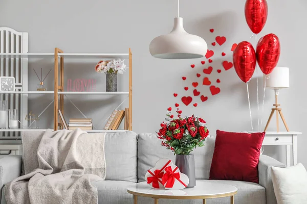 Interior of living room decorated for Valentine\'s Day with sofa, flowers and balloons