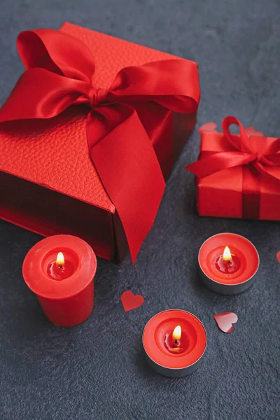 Burning candles and gift boxes on dark background, closeup. Valentine\'s Day celebration
