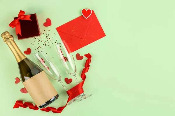 Bottle of wine, glasses, gift and envelope on green background. Valentine\'s Day Celebration