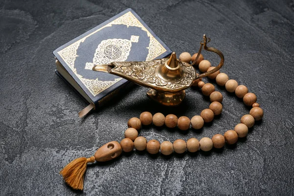 Aladdin lamp of wishes, Koran and prayer beads for Ramadan on dark background