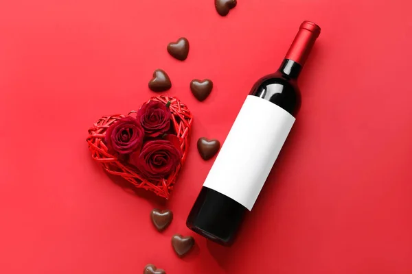 Bottle of wine, chocolate candies and rose flowers on red background. Valentine\'s Day celebration