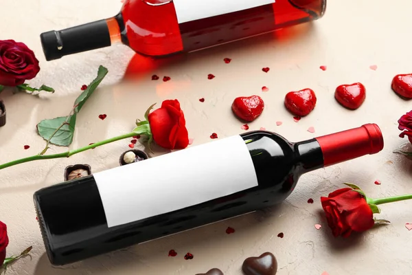 Bottles of wine, chocolate candies and rose flowers on beige background. Valentine\'s Day celebration