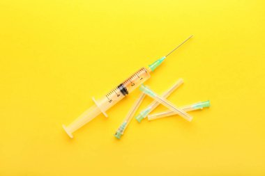 Medical syringe with needles on yellow background