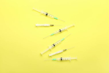 Empty medical syringes on yellow background
