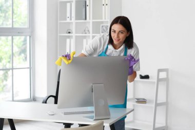Female janitor wiping computer in office
