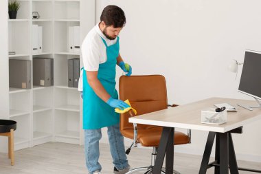 Male janitor cleaning chair in office