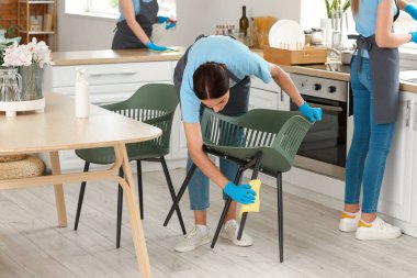 Female janitor cleaning chair in kitchen