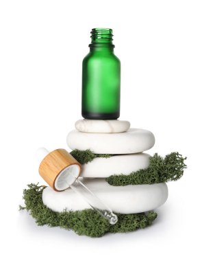 Cosmetic dropper bottle with green moss and spa stones on white background