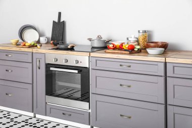 Interior of modern kitchen with grey counter, oven and food