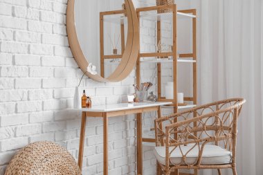 Interior of stylish makeup room with table, mirror and shelving unit