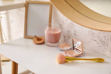 Table with brushes, cosmetics, frame and candle in makeup room