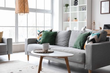 Interior of modern living room with grey sofa, table and shelving unit