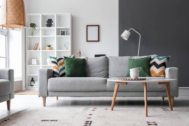 Interior of modern living room with grey sofa, table and shelving unit