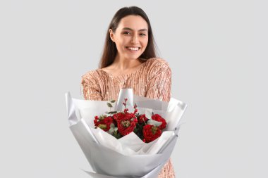 Young woman with bouquet of flowers on light background. Valentine's Day celebration