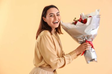 Young woman with bouquet of flowers on beige background. Valentine's Day celebration