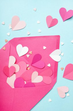 Envelope with paper hearts on blue background. Valentines Day celebration