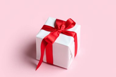 Gift box with beautiful bow on pink background. Valentine's Day celebration