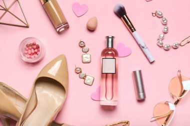 Perfume with accessories, makeup products and heels for Valentine's day on pink background