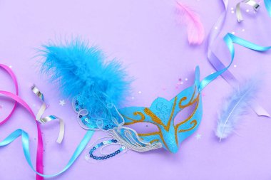 Carnival mask with confetti and serpentine on lilac background
