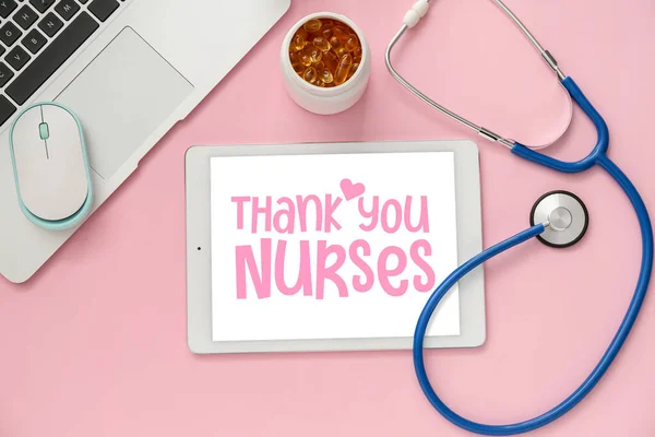 Tablet computer with text THANK YOU NURSES on screen, stethoscope and pills on pink background