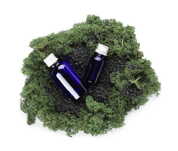 Cosmetic dropper bottles with green moss on white background