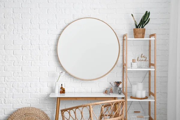 Interior of stylish makeup room with table, mirror and shelving unit