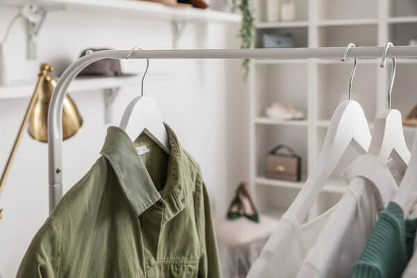 Стойка со стильной одеждой в светлой гримерке, крупным планом