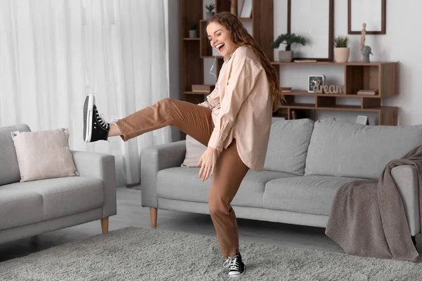 Young woman in earphones dancing at home
