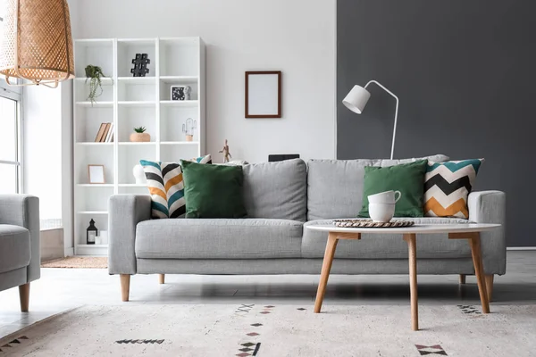 Interior of modern living room with grey sofa, table and shelving unit