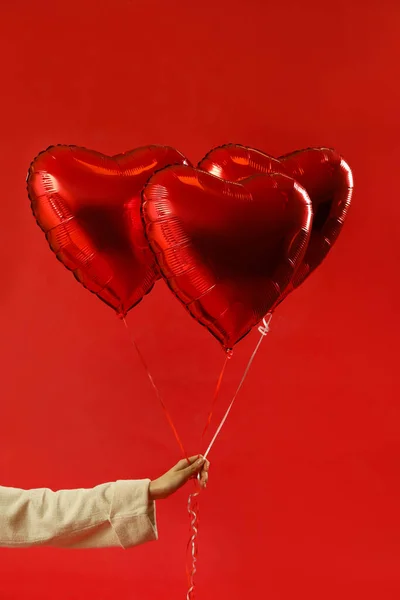 Woman with heart shaped balloons for Valentine's Day on red background
