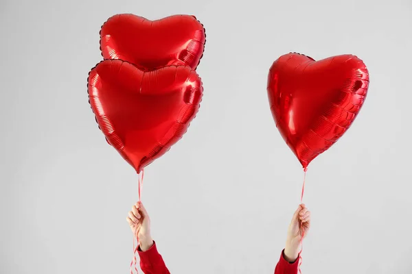 Woman with heart shaped balloons for Valentine\'s Day on light background