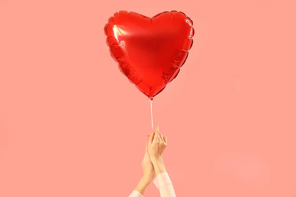 Woman with heart-shaped balloon for Valentine\'s Day on pink background