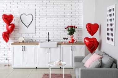Interior of kitchen decorated for Valentine's Day with counters, sofa and candles