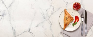 Plate with tasty Uzbek samsa and tomato sauce on light background with space for text