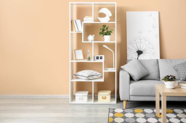 Interior of stylish living room with grey sofa, table and shelving unit