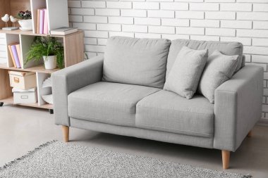 Grey sofa near white brick wall in living room