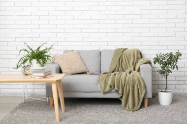 Interior of modern living room with grey sofa, table and houseplants