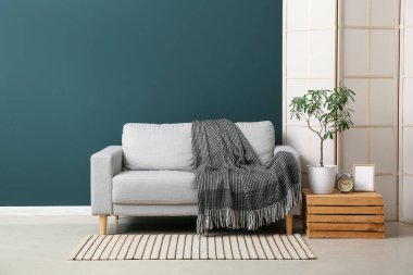 Interior of stylish living room with grey sofa, wooden box and folding screen