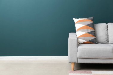 Grey sofa with cushion near green wall