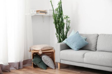 Aydınlık oturma odasının içindeki yastıklı gri kanepe.