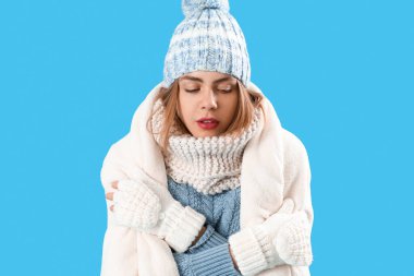 Frozen young woman in warm plaid on blue background