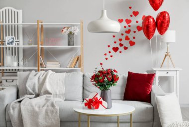 Interior of living room decorated for Valentine's Day with sofa, flowers and balloons