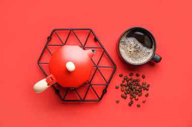 Metallic board with geyser coffee maker, cup and beans on red background